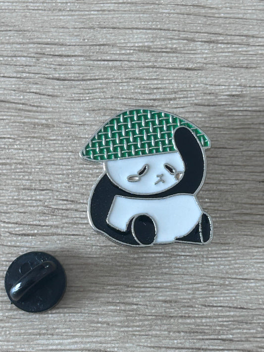 Broche panda au chapeau de paille vert tissé, avec tête blanche et épingle noire.
