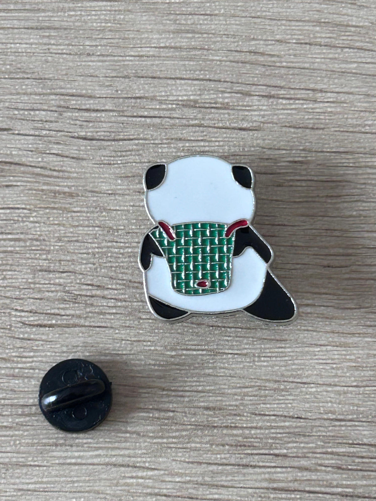 Épinglette panda sac à dos vert, contour noir, fond blanc, style émail