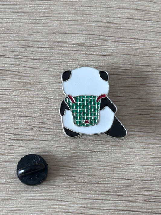 Épinglette panda sac à dos vert, contour noir, fond blanc, style émail