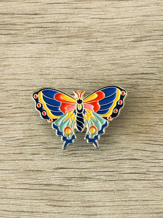 Broche papillon émaillée multicolore, contours dorés et ailes bleu/orange.
