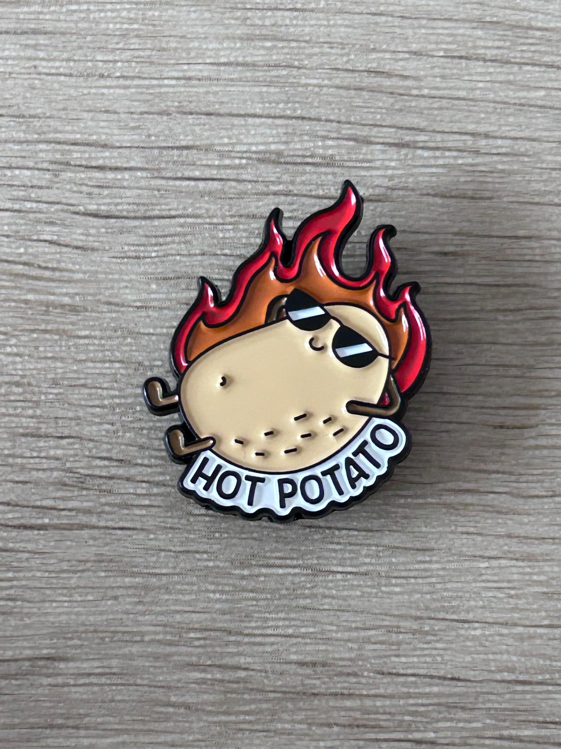 Épingle émaillée motif patate en flammes rouge et noire, inscription HOT POTATO.