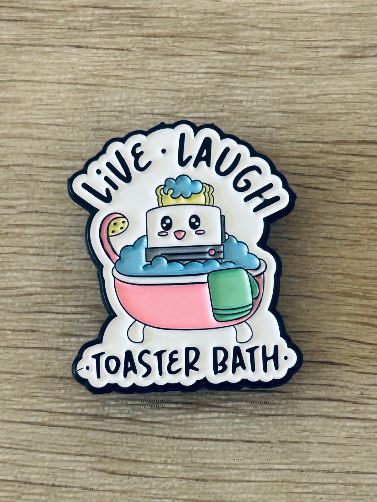 Pin émaillé en forme de toaster dans une baignoire, motif “Toastier Bath”.