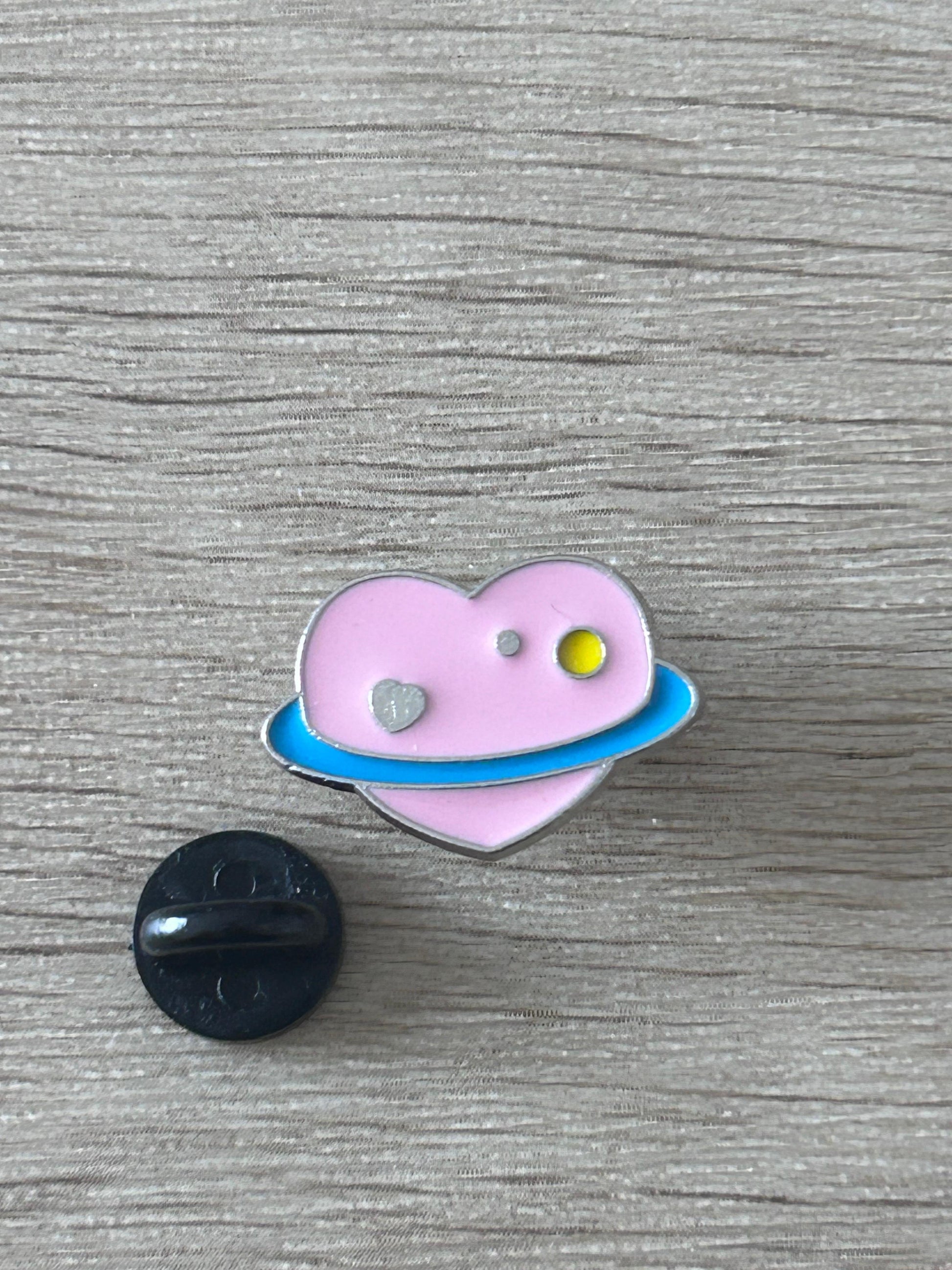 Épingle cœur planète violette avec petit disque argenté et motif ovale bleu