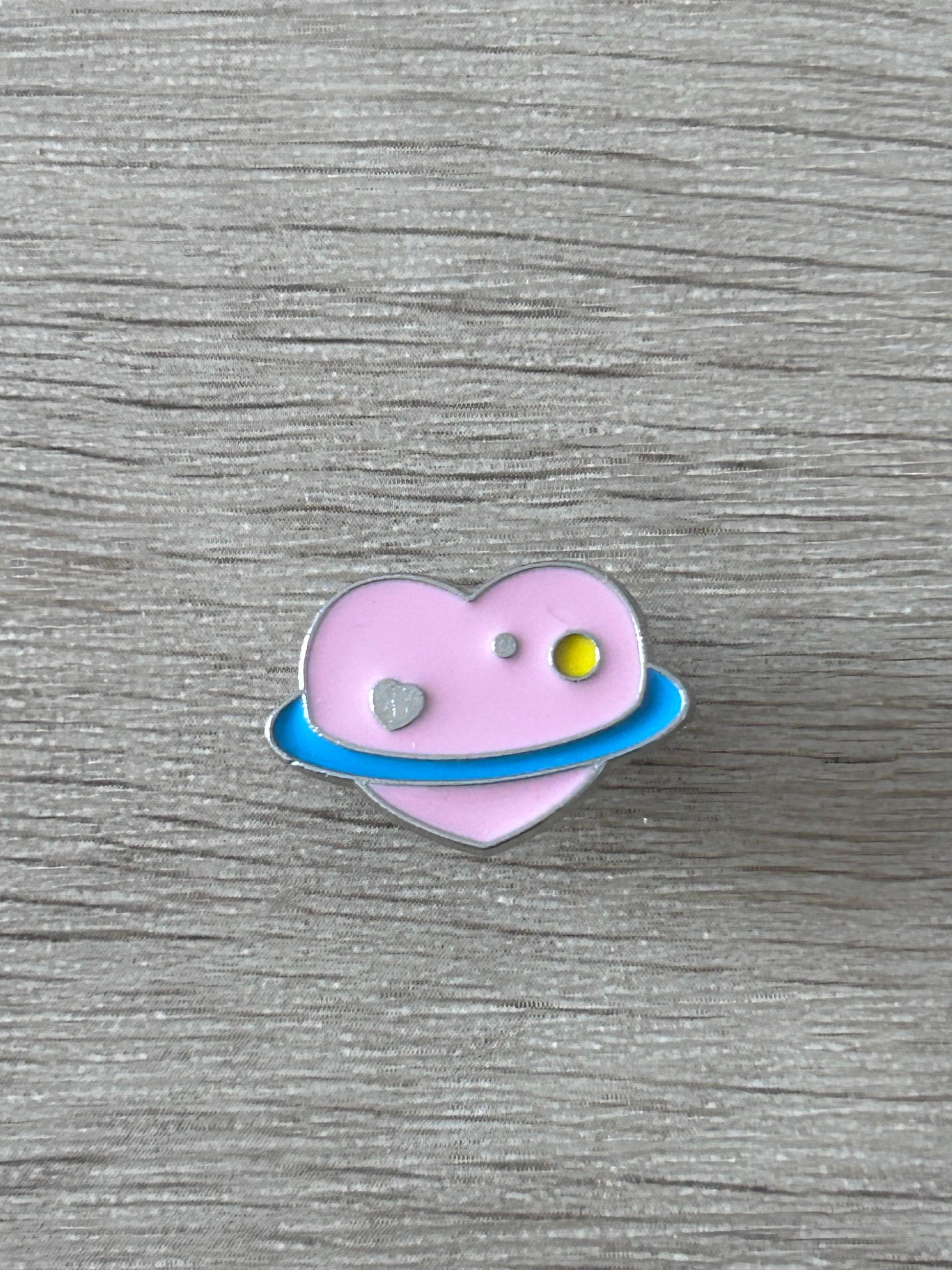 Épingle en forme de cœur violet avec planète jaune et anneau bleu
