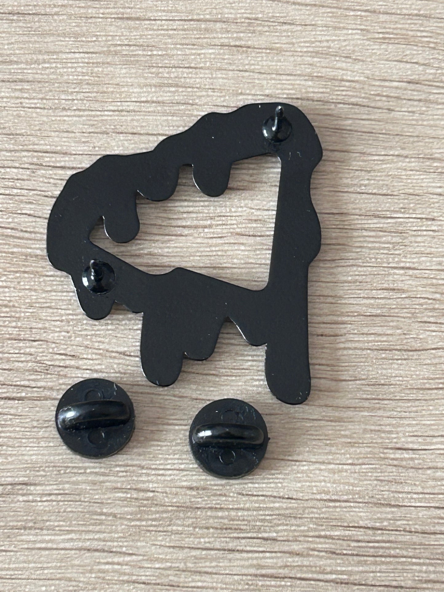 Épinglette noire silhouette dégoulinante avec attaches arrière