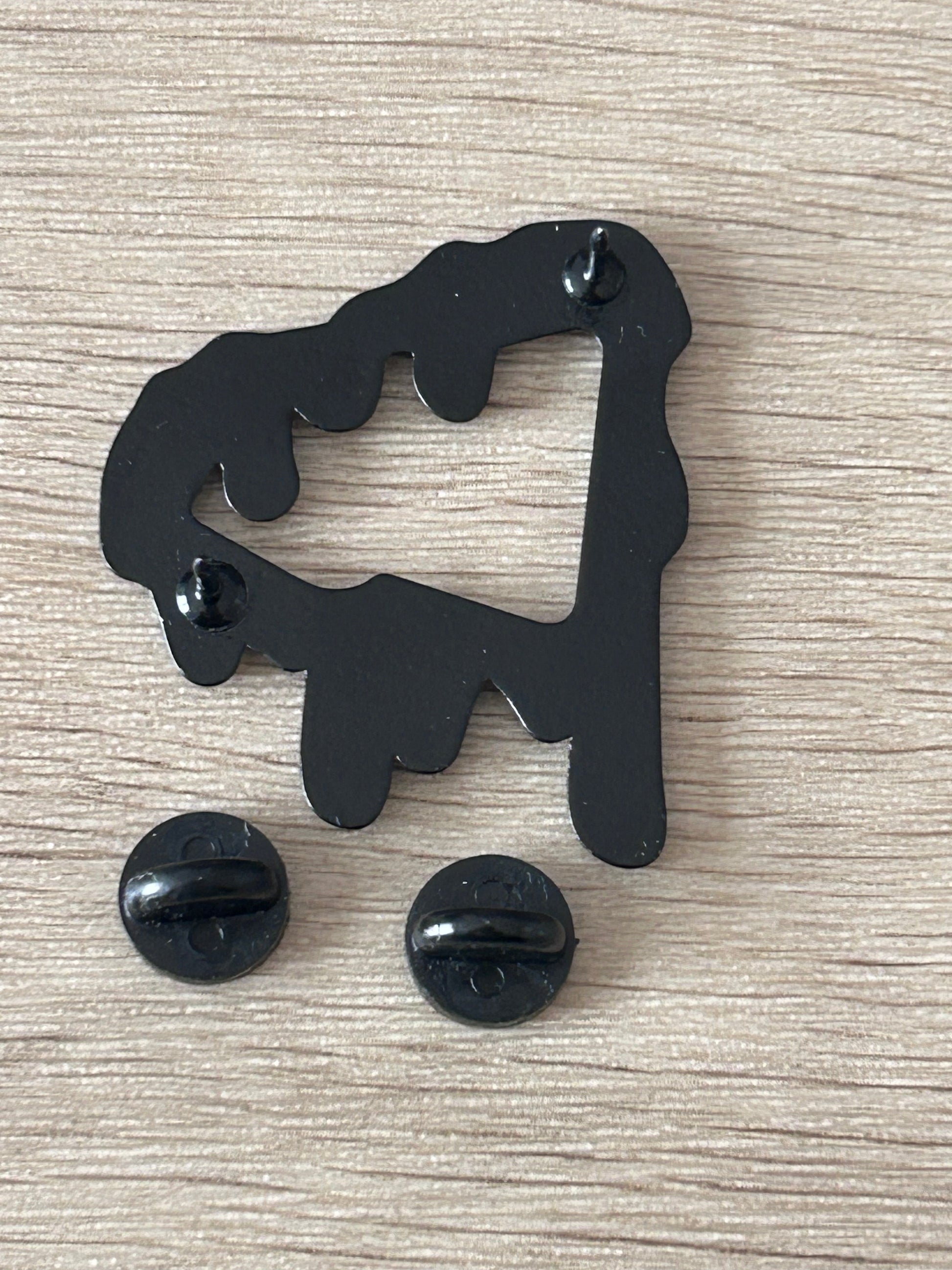 Épinglette noire silhouette dégoulinante avec attaches arrière