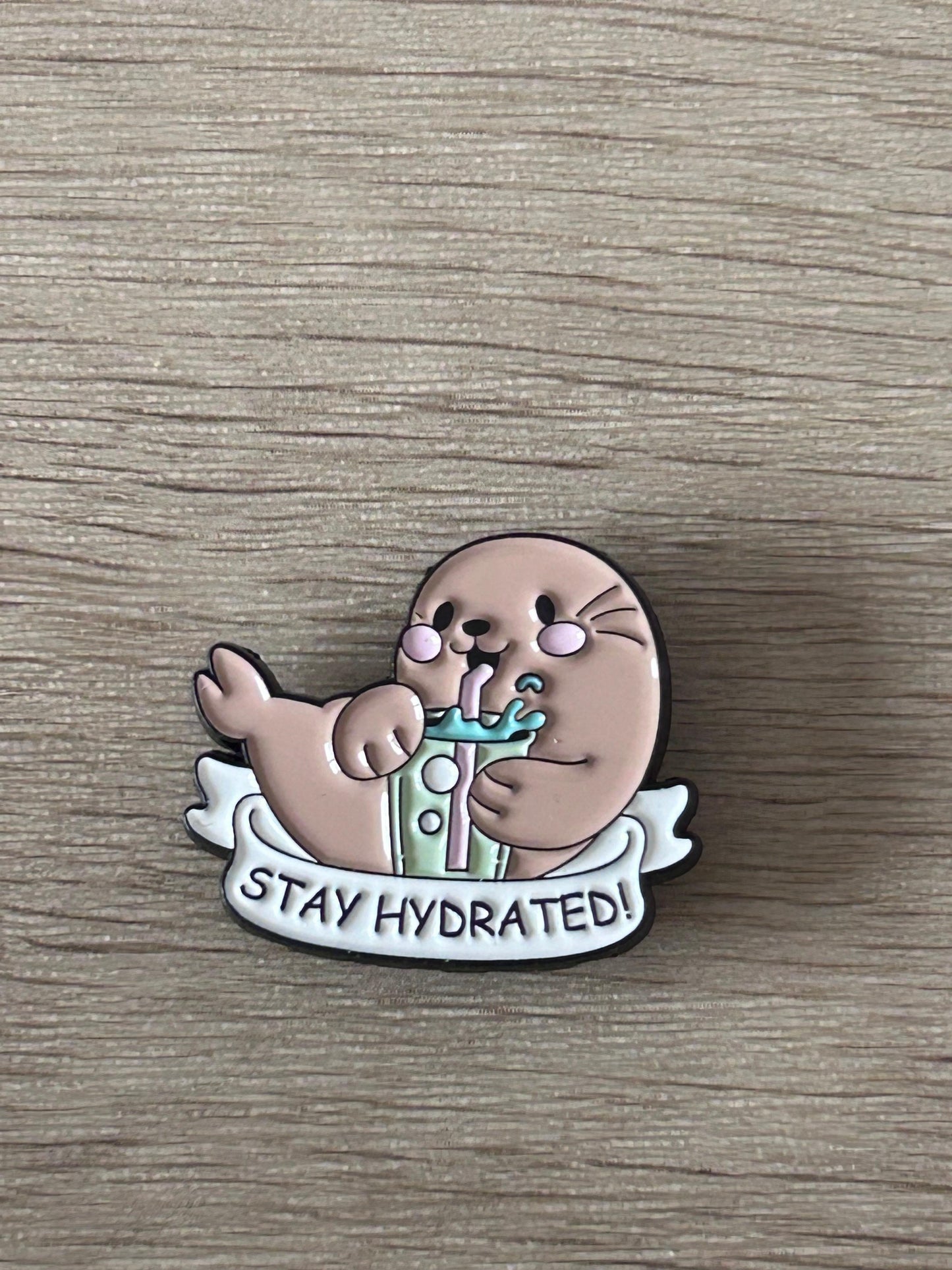 Badge épingle phoque gris « Stay Hydrated ! » avec bouteille et ailes