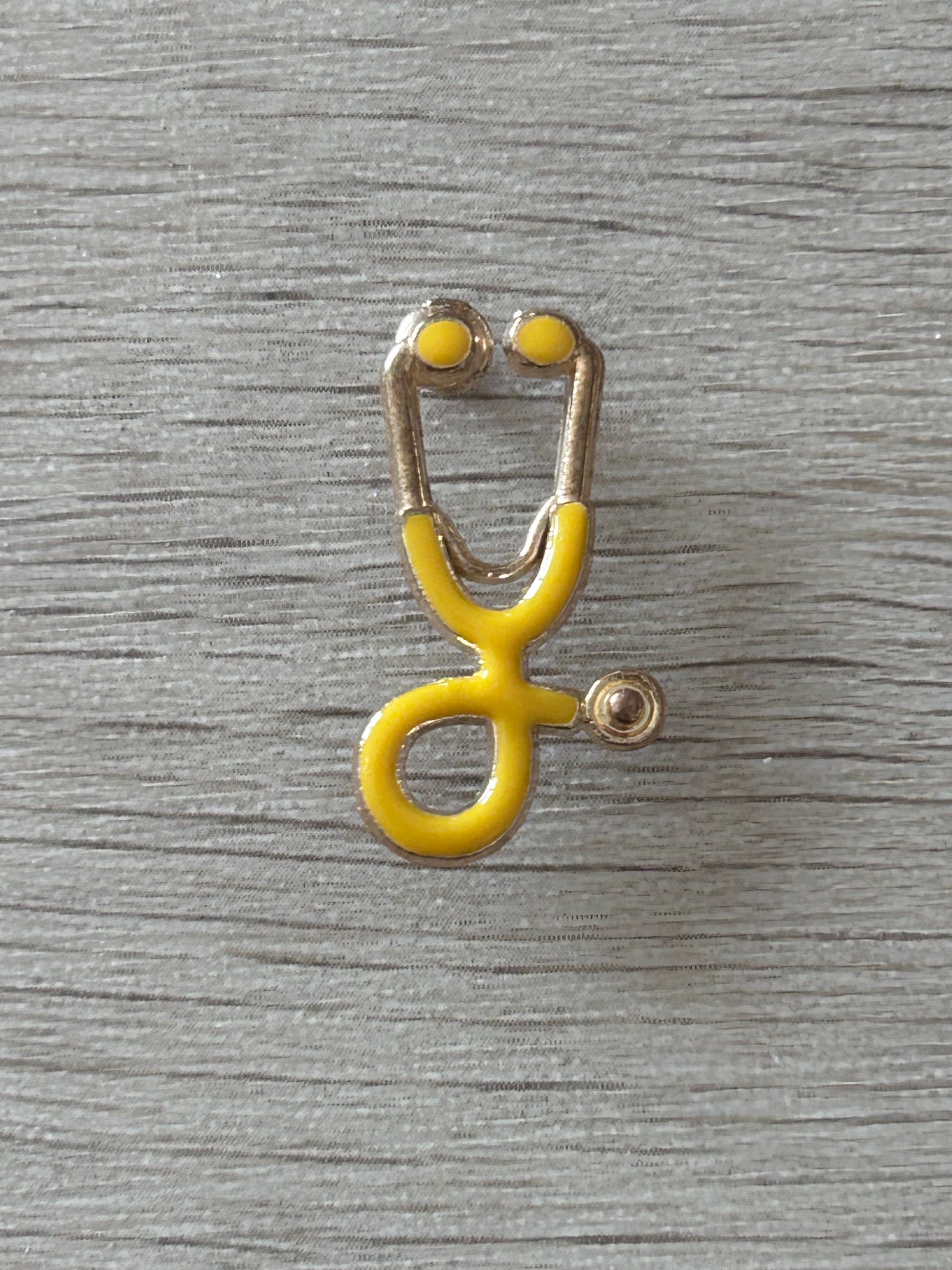 Pin's stéthoscope jaune, contour doré, fixation papillon
