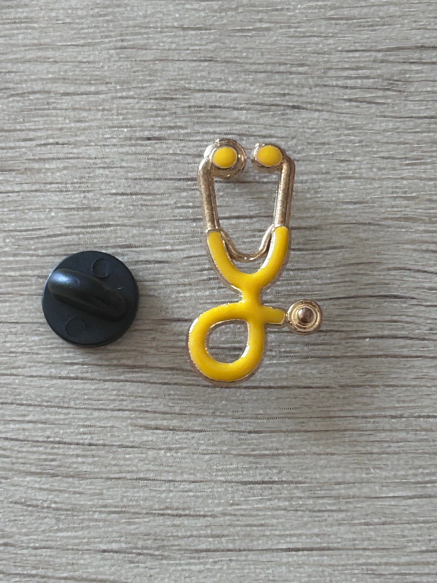 Pin's stéthoscope jaune vue de face, émail jaune et contour doré