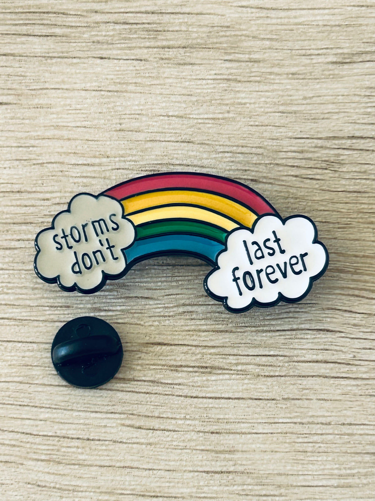 Pin arc-en-ciel avec nuages «storms don't» et «last forever», dos noir