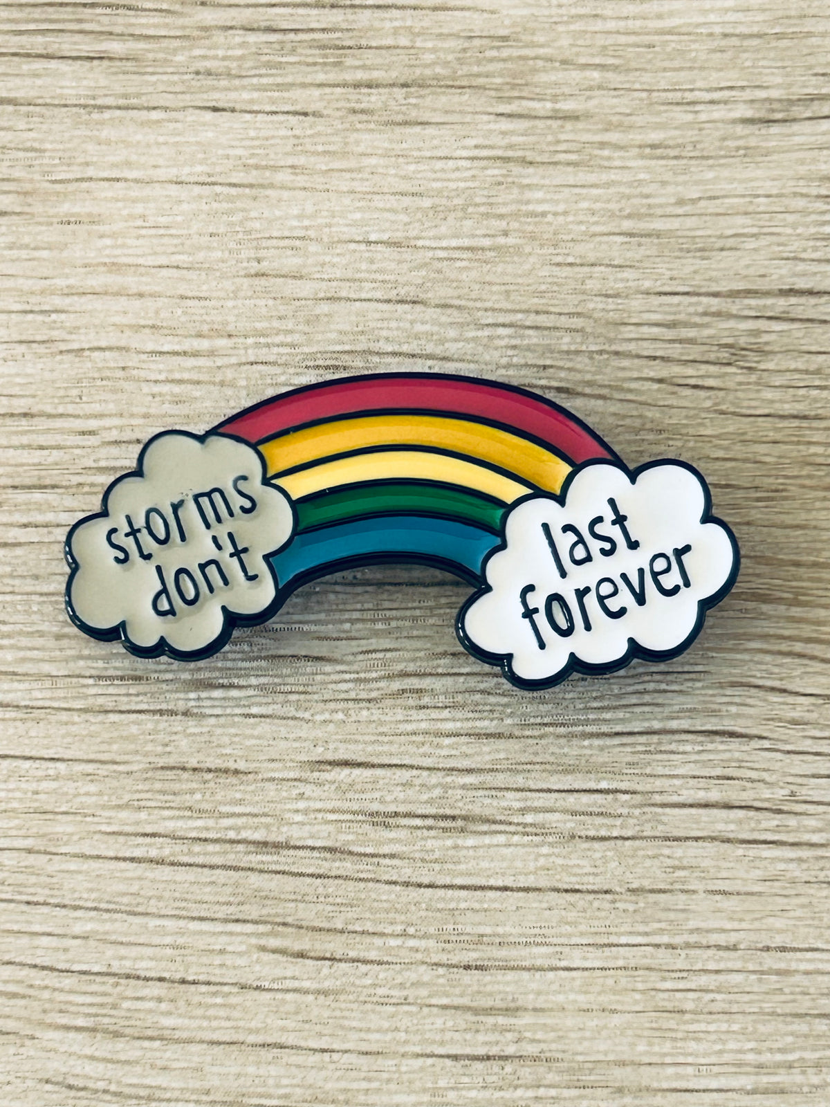 Pin arc-en-ciel avec nuages «storms don't» et «last forever»