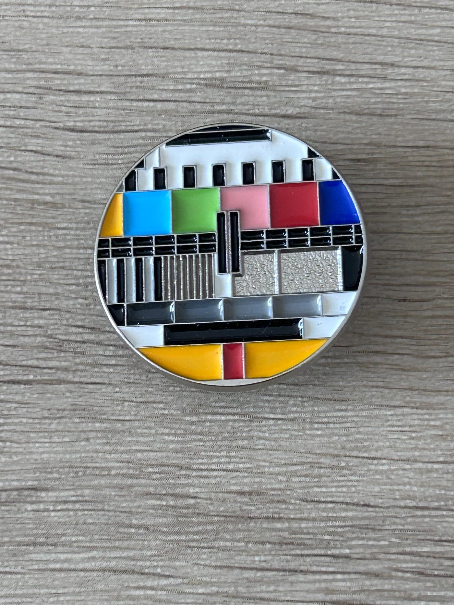 Pin's rond avec motif mire TV en bandes colorées et fond argenté